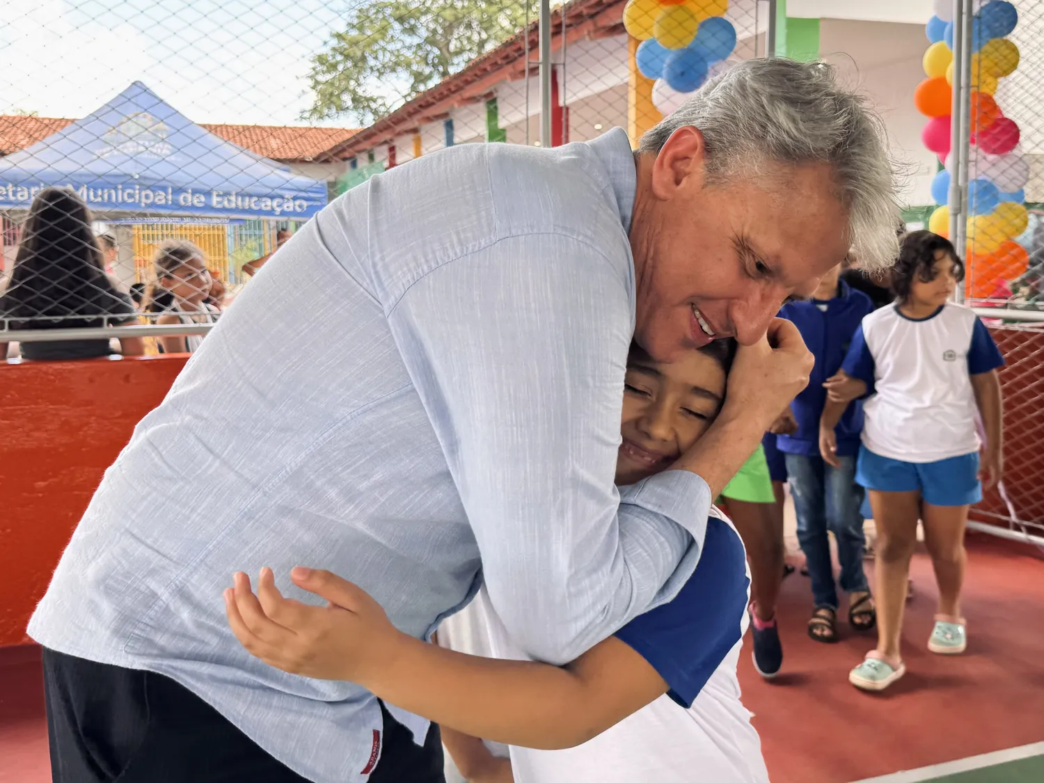 Vereador Isaías Ribeiro abraça uma criança na inauguração de uma quadra escolar